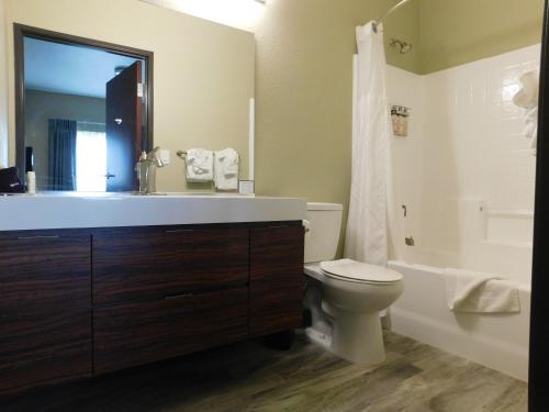 a bathroom with a sink and a toilet and a mirror at Island Suites in Lake Havasu City