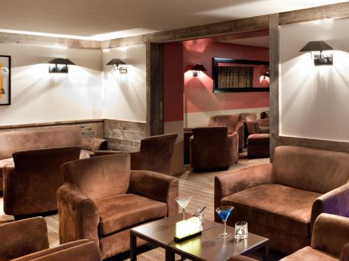 a bar with brown leather chairs and a table at Hôtel Vanessa in Verbier