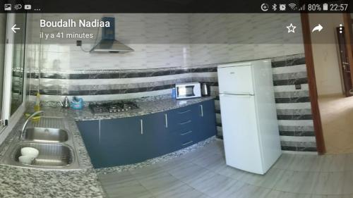 uma cozinha com armários azuis e um frigorífico branco em Appartement Haron em Kenitra