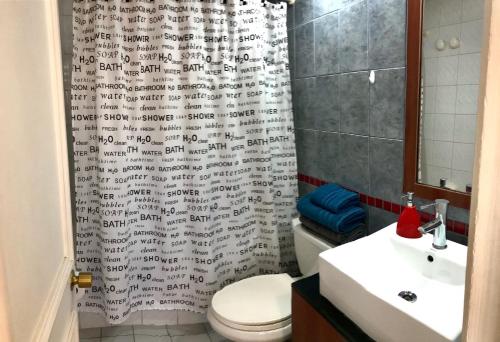 a bathroom with a shower curtain with a toilet and a sink at Estudio en el Golf in Santiago