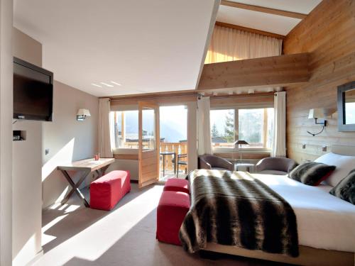 sypialnia z dużym łóżkiem i dużym oknem w obiekcie Hôtel Vanessa w mieście Verbier