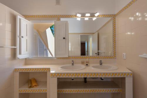 a bathroom with two sinks and a large mirror at Lovely Rustic Casa Catita with amazing roof terrace views in Tavira