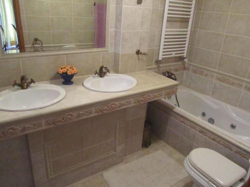 een badkamer met 2 wastafels, een bad en een toilet bij Vivenda Marinho Wix in Porto