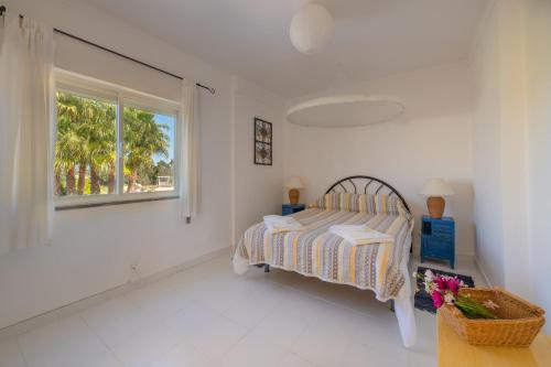a white bedroom with a bed and a window at Ceu Azul - Elevated apartment with stunning views and big garden - Somewhere Special in Tavira