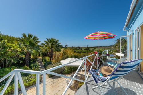 a balcony with two chairs and an umbrella at Ceu Azul - Elevated apartment with stunning views and big garden - Somewhere Special in Tavira