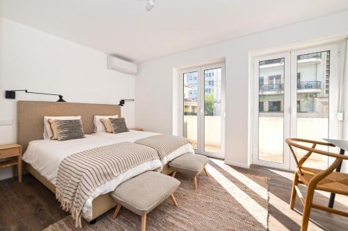a white bedroom with a bed and a chair at The Albuquerque Suites Self Check in in Lisbon