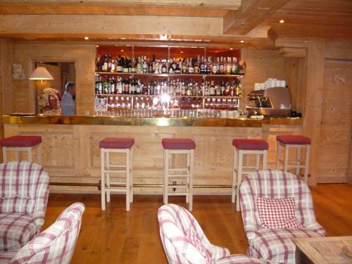 a bar with four stools and a counter with alcohol at Aux Ducs de Savoie in Combloux