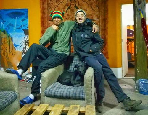 two people sitting on a chair with a dog at Monkeywasi Climbing Hostel in Huaraz