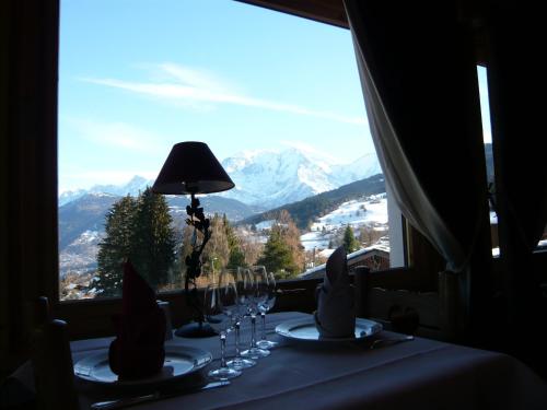a table with wine glasses and a view of a mountain at Aux Ducs de Savoie in Combloux