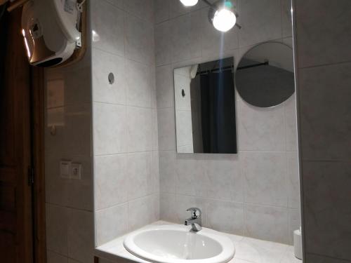 La salle de bains est pourvue d'un lavabo et d'un miroir. dans l'établissement Appartement château Uriage-Chamrousse, à Saint-Martin-dʼUriage