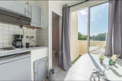 une cuisine blanche avec vue sur un balcon dans l'établissement Grand appartement doté d'une terasse avec magnifique vue, à Montpellier