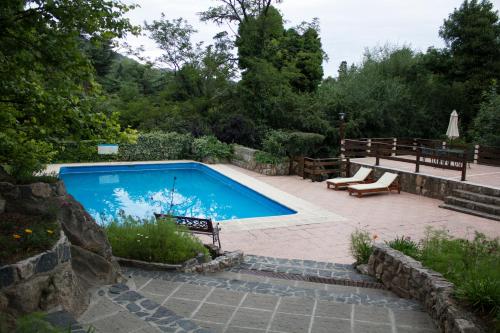 una piscina en un jardín con un banco y una mesa en Solares Cumbrecita Hotel & Apart en La Cumbrecita