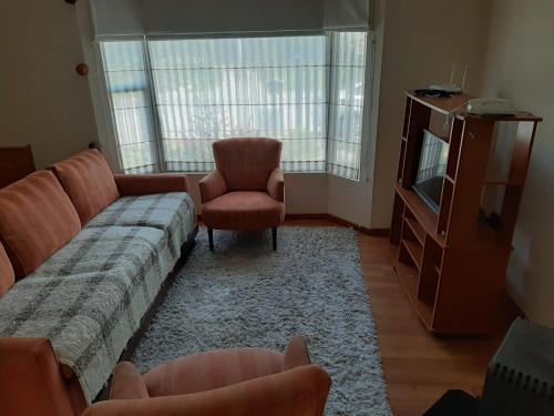 sala de estar con sofá, TV y silla en Quimantu, en Puerto Varas