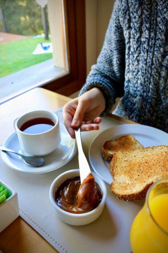 Hosteria Las Garzas في فيلا لا أنجوستورا: شخص يجلس على طاولة مع فنجان قهوة وقطعة خبز محمص