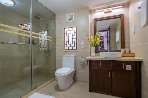 a bathroom with a toilet and a shower and a sink at Doof Resort Hotel in Lijiang