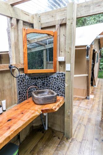 a bathroom sink with a mirror on a wooden table at Rhino's Retreat in Waipapa