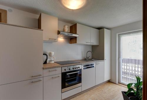 a kitchen with white cabinets and a stove top oven at Apartments Gasteiger in Lutago