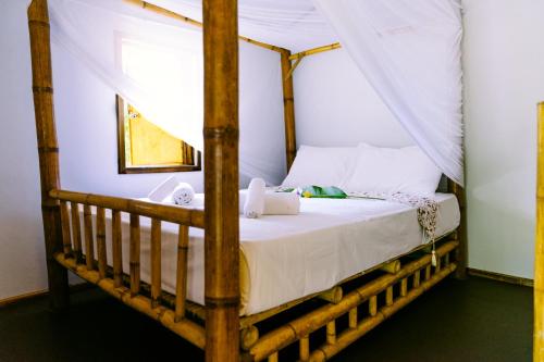 a bedroom with a canopy bed with a laptop on it at Orion Healing Centre in Srithanu