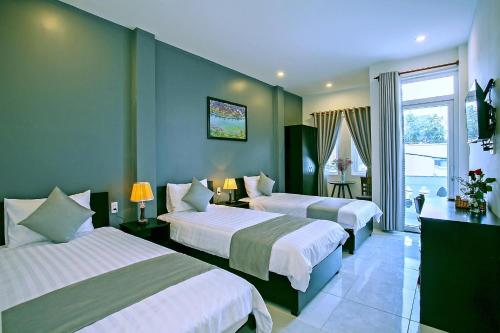 una camera d'albergo con tre letti e una finestra di Focus Homestay a Hoi An