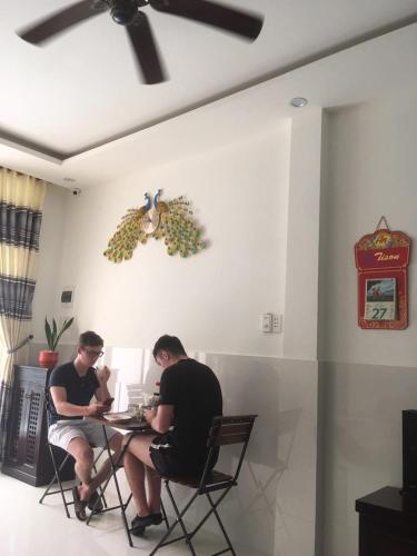 dois homens sentados numa mesa numa sala em Focus Homestay em Hoi An