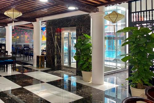 a restaurant with a black and white tile floor and plants at Thanh Binh Central Hotel in Hoi An