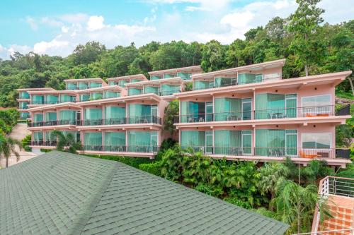 an apartment building on a hill with trees at The View Rawada Phuket in Rawai Beach