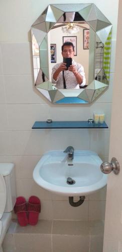 a man taking a picture of a sink in a bathroom at Two-Bedroom at San Remo Oasis in Cebu City