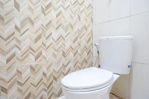 a bathroom with a white toilet in a room at RedDoorz @ Hotel Bumi Palupy in Palu