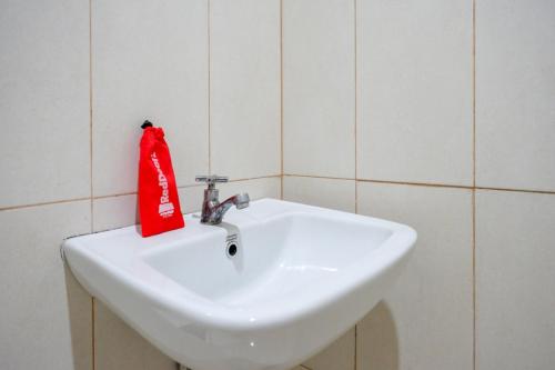a white bathroom sink with a red bag on it at RedDoorz @ Hotel Bumi Palupy in Palu