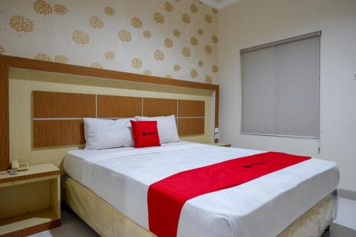 a bedroom with a large white bed with a red blanket at RedDoorz @ Hotel Bumi Palupy in Palu