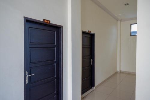 two black doors in a room with a hallway at RedDoorz @ Hotel Bumi Palupy in Palu