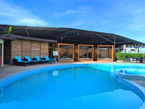 a large swimming pool with blue chairs and a building at Pacific Crown Hotel in Honiara