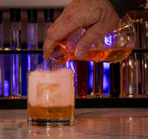 a person pouring a drink into a glass at Hotel Indigo - Birmingham Five Points S - UAB by IHG in Birmingham