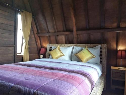 a bedroom with a large bed with wooden walls at Ti Amo Bali in Jatiluwih