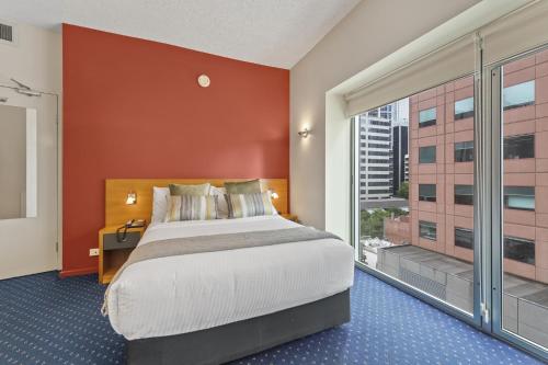 - une chambre avec un grand lit et une grande fenêtre dans l'établissement YEHS Hotel Melbourne CBD, à Melbourne