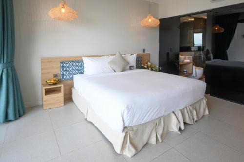 a bedroom with a large white bed and a bathroom at Loloata Island Resort in Loloata Island