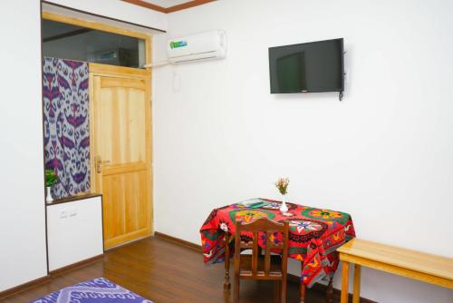 a dining room with a table and a television at Little Bukhara in Bukhara
