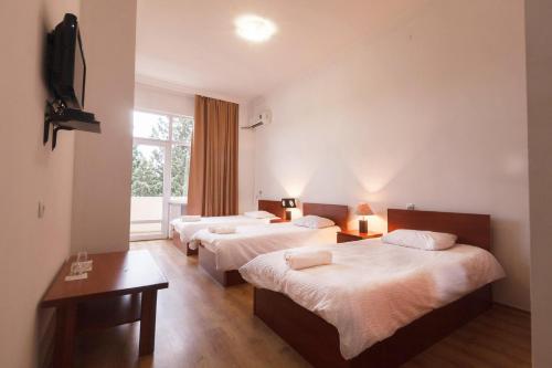 ein Hotelzimmer mit 3 Betten und einem Fenster in der Unterkunft Ortachala Palace in Tbilisi City