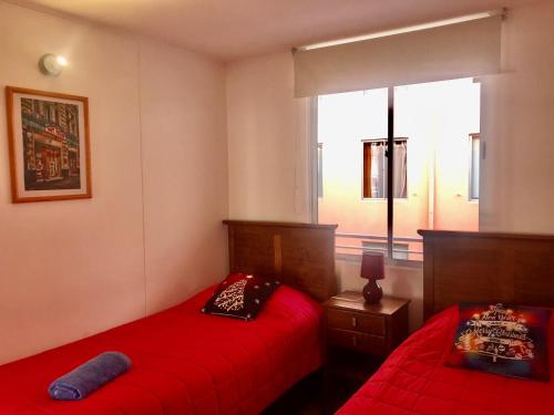 a bedroom with two red beds and a window at Cosmopolita Rojo in La Serena