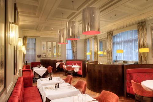 a restaurant with tables and red chairs and a bar at Hotel Indigo Glasgow, an IHG Hotel in Glasgow