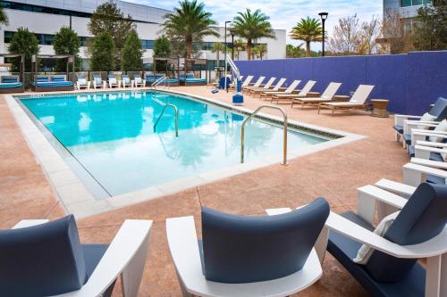una piscina con tumbonas y sillas alrededor en Hotel Indigo Gainesville-Celebration Pointe, an IHG Hotel en Gainesville