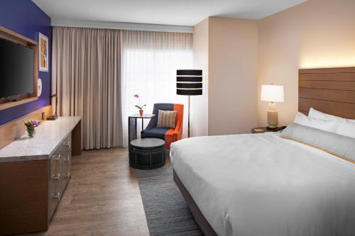a hotel room with a large bed and a chair at Hotel Indigo Gainesville-Celebration Pointe by IHG in Gainesville