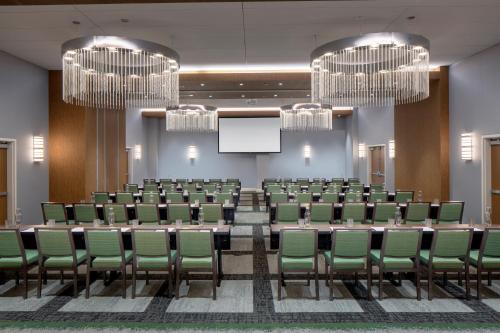 a conference room with green chairs and a projection screen at Hotel Indigo Gainesville-Celebration Pointe by IHG in Gainesville