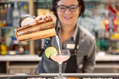 a woman is pouring a drink into a glass at Hotel Indigo Gainesville-Celebration Pointe by IHG in Gainesville