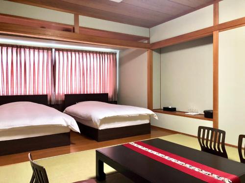 a bedroom with two beds and a table and chairs at Hotel Takasago in Kochi