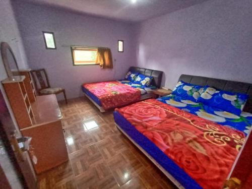 a bedroom with two beds and a chair in it at Elen Homestay by ABM in Bromo