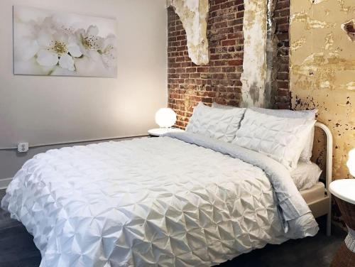 Un dormitorio con una cama blanca y una pared de ladrillo. en Downtown Retreat - Location - Comfort - Style, en Atlanta