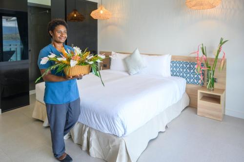 a man standing next to a bed with a basket of flowers at Loloata Island Resort in Loloata Island