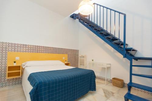 a bedroom with a bed and a blue staircase at BOHEMIA SANLUCAR in Sanlúcar de Barrameda
