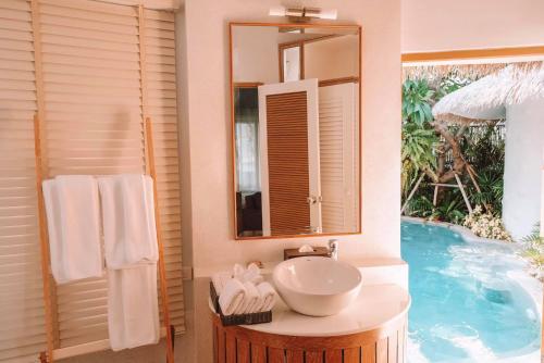 uma casa de banho com um lavatório e um espelho ao lado de uma piscina em Kundala Beach Resort Hua Hin em Hua Hin